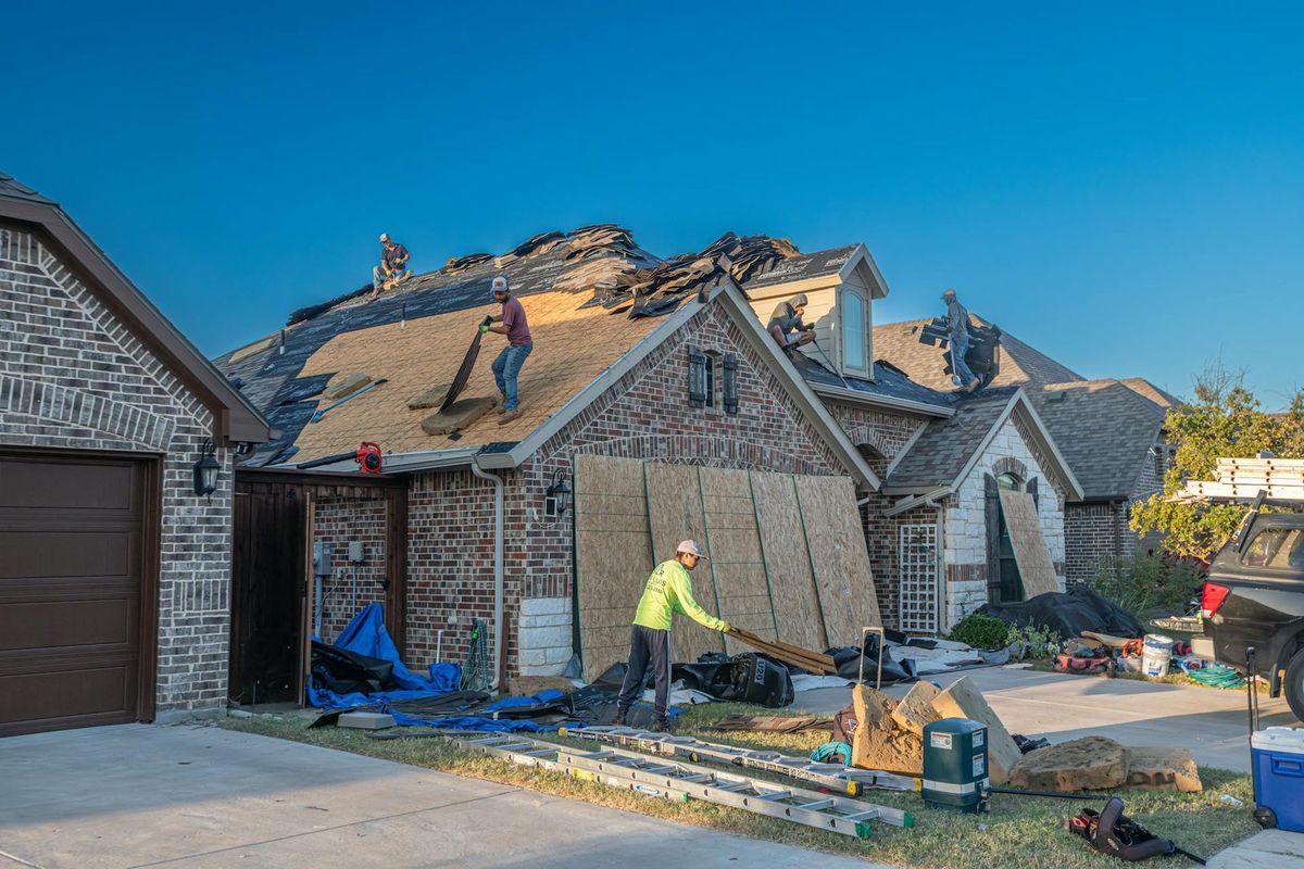 Roofers replacing a roof on a brick home